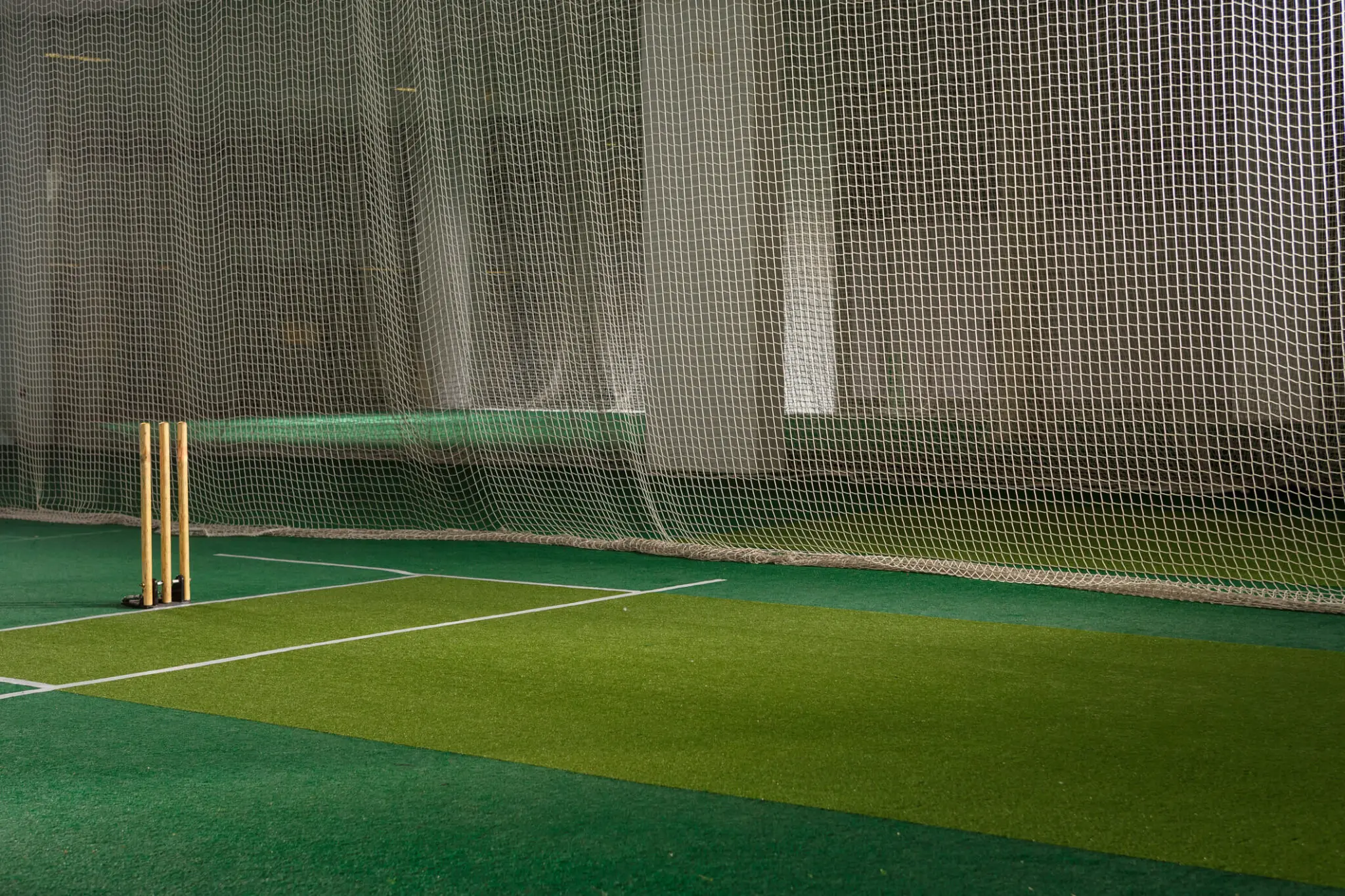 Indoor cricket net with wooden stumps.
